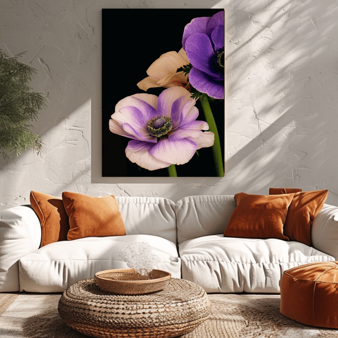 De afbeelding toont een stijlvol woonkamerinterieur met een zachte, warme sfeer. Aan de wand hangt een kunstwerk met paarse en roze-lila anemoonbloemen tegen een zwarte achtergrond - dezelfde bloemen die we in de eerdere afbeeldingen zagen. De wand is gemaakt van wit pleisterwerk met een lichte textuur, waarop een mooi schaduwspel van zonlicht valt.