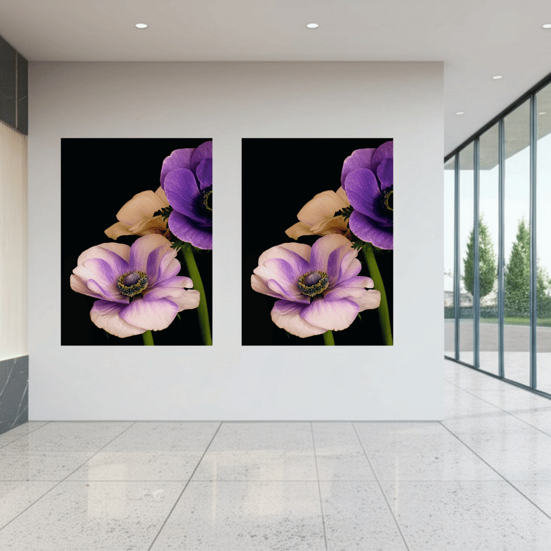De afbeelding toont een minimalistisch, modern interieur met een witte muur waarop twee identieke kunstwerken naast elkaar hangen. De kunstwerken tonen paarse en roze-lila anemoonbloemen tegen een zwarte achtergrond - dezelfde bloemen die we eerder zagen in de keukenopstelling. De ruimte heeft een lichte terrazzovloer en grote raampartijen aan de rechterkant die uitzicht bieden op bomen buiten. De inrichting is strak en eenvoudig, met inbouwverlichting in het plafond.