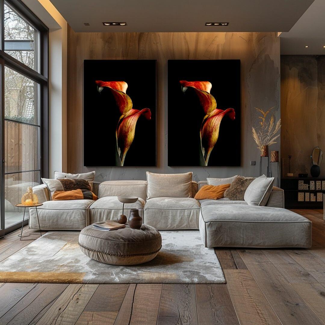 Twee identieke calla lelie kunstprints boven moderne grijze bank in luxe woonkamer met houten accenten en warme oranje decoratie details