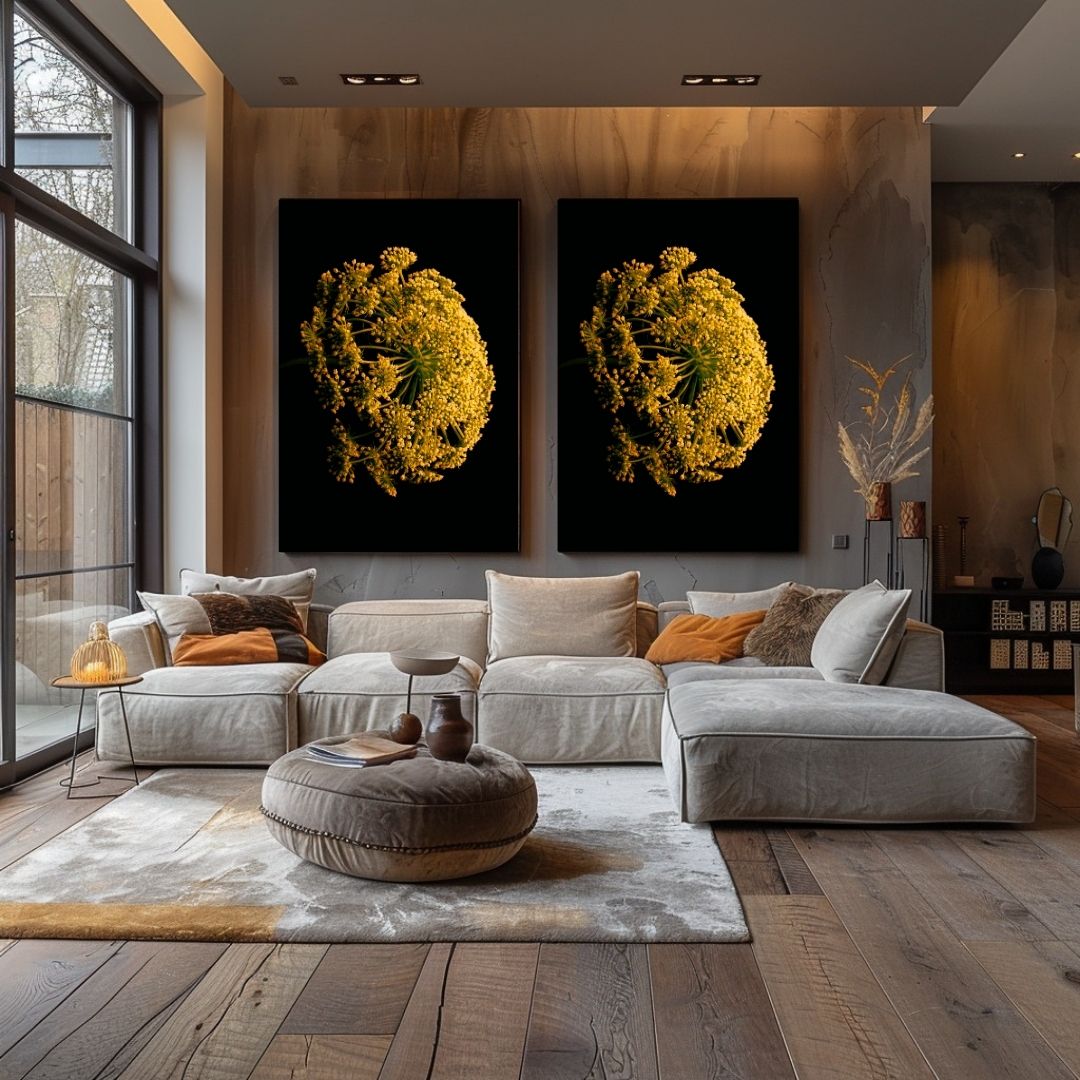 Moderne woonkamer met twee identieke zwart-gele zevenblad kunstwerken boven een lichtgrijze loungebank. Warme houten wanden en vloer, grote ramen links, en minimalistisch interieur met enkele sierkussens in oranje en neutrale tinten. Een ronde poef staat op een licht tapijt in het midden van de ruimte.